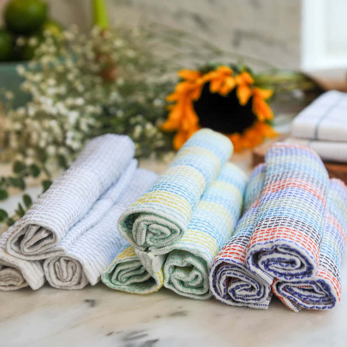 Set of colourful folded towels on a marble surface with decorative sunflower and plants in the background.