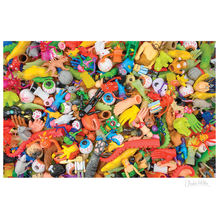 The Toy Explosion Puzzle features a vibrant mix of assorted plastic toy body parts and Archie McPhee toys, creating a chaotic scene reminiscent of a 1000-piece puzzle.