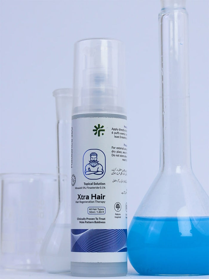 Xtra Hair product bottle with a blue liquid in a beaker on a light gray background